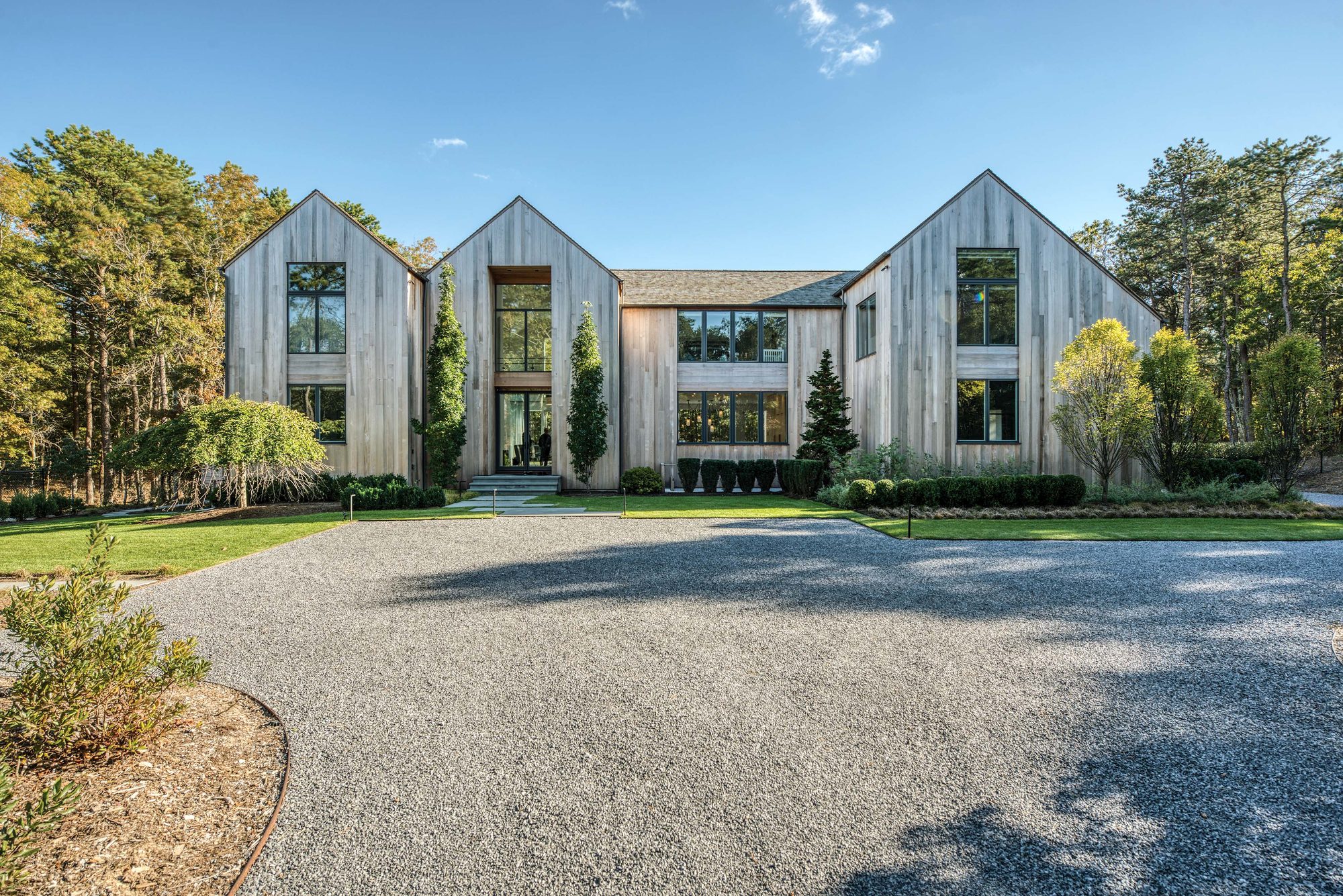 Three bleached cedar gables rising above a wide gravel court