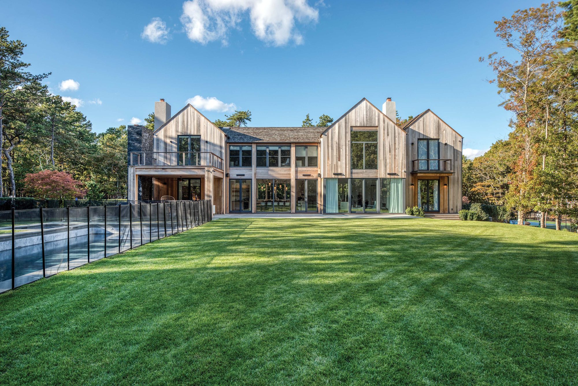 Rear elevation of cedar gables and tall glazing across a broad lawn