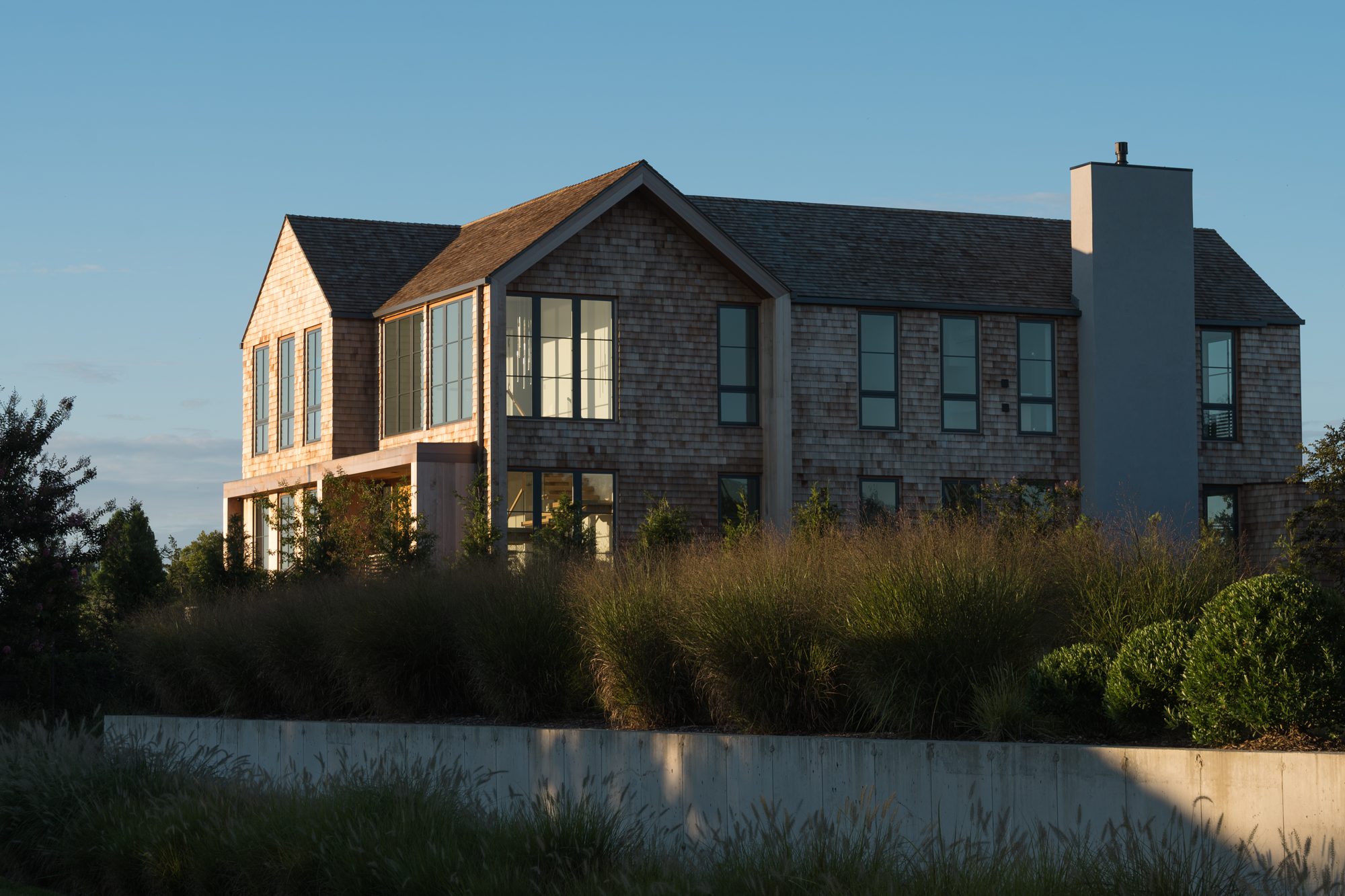 Shingled facade and chimney rising above native grasses