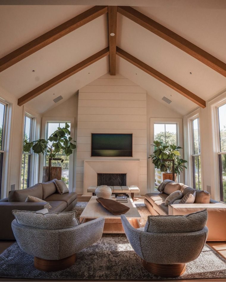 Vaulted living room with exposed beams, fireplace and swivel chairs