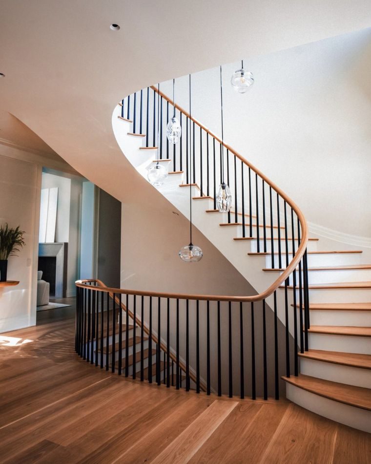 Curving white stair with dark iron balusters and oak treads