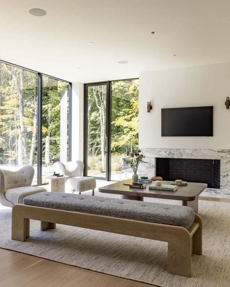 Sunlit living room with floor-to-ceiling glass and a marble fireplace