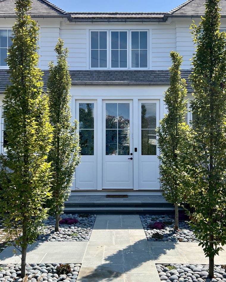 White French doors between columnar trees and a bluestone walk