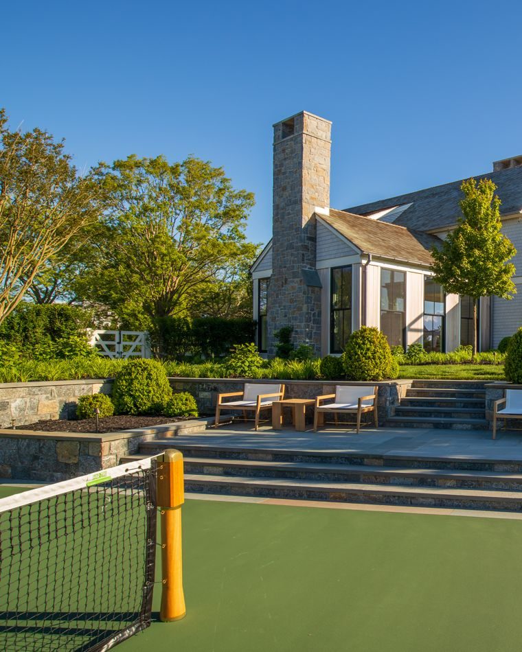 Stone chimney and terraced patio above a tennis court