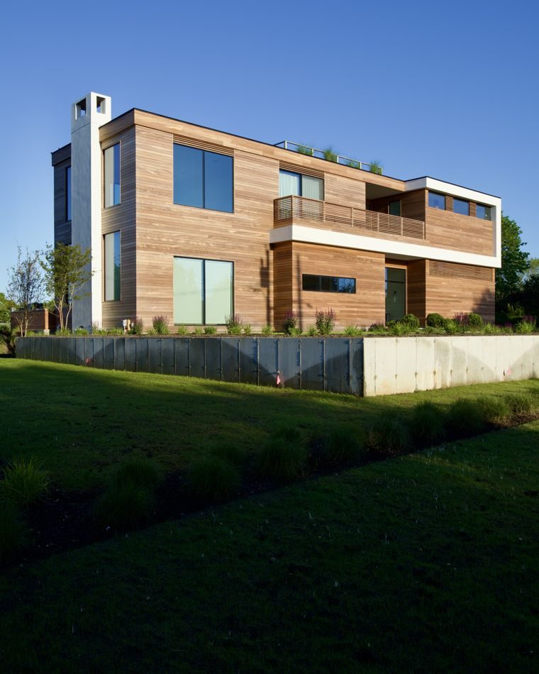 Modern cedar-clad house with a roof deck on a green lawn