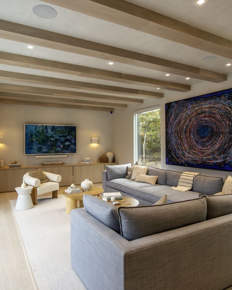 Family room with beamed ceiling, grey sectional and a large abstract painting